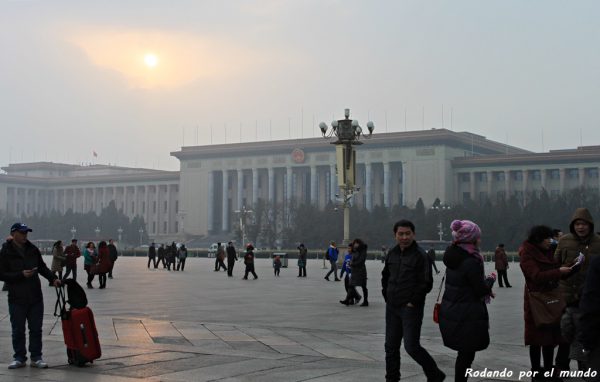 Tras la nube de contaminación que tamiza la luz del sol se levanta el Gran Palacio del Pueblo.